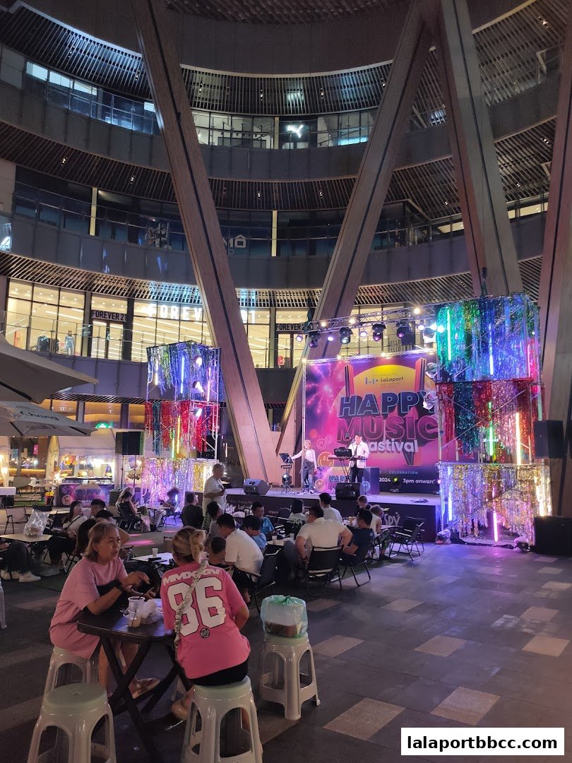 People enjoy a live music performance at an outdoor festival in a modern shopping plaza.