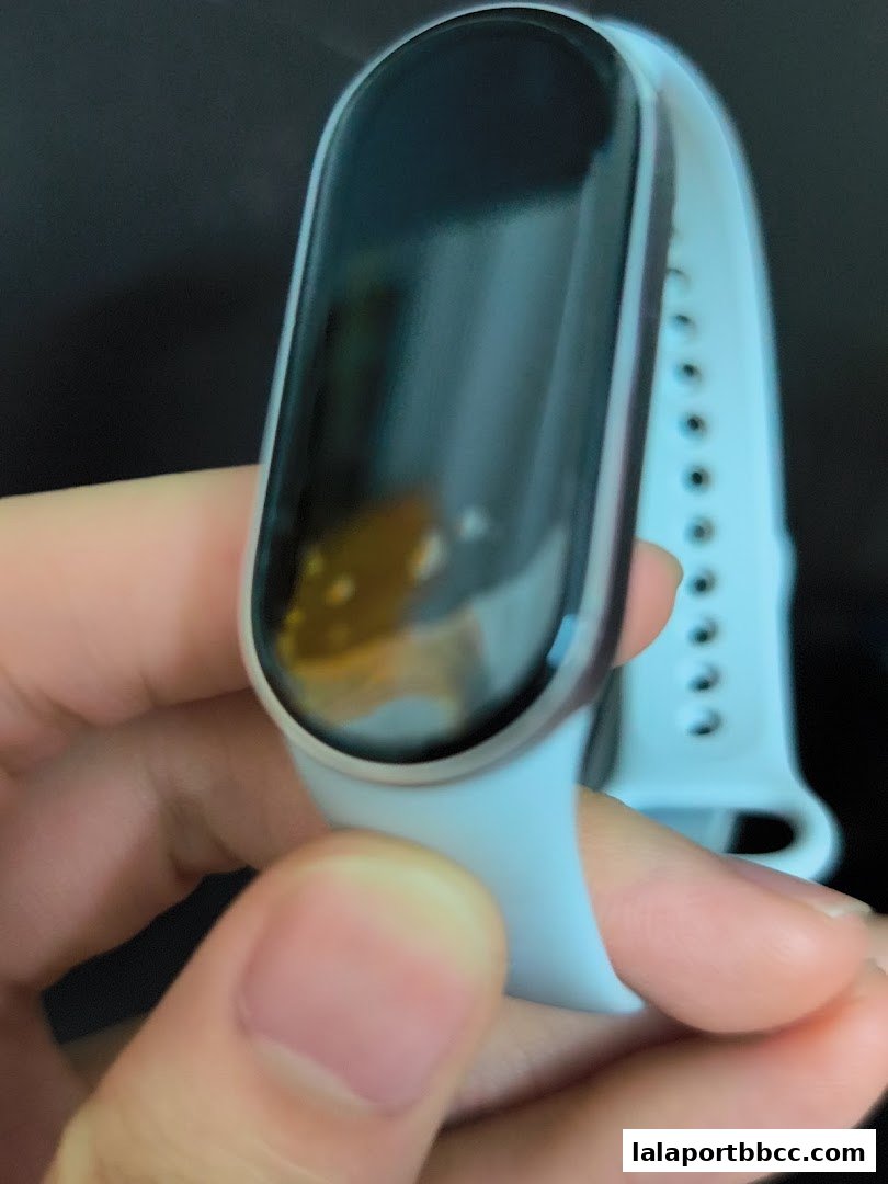 A hand holds a light blue fitness tracker with a dark screen.