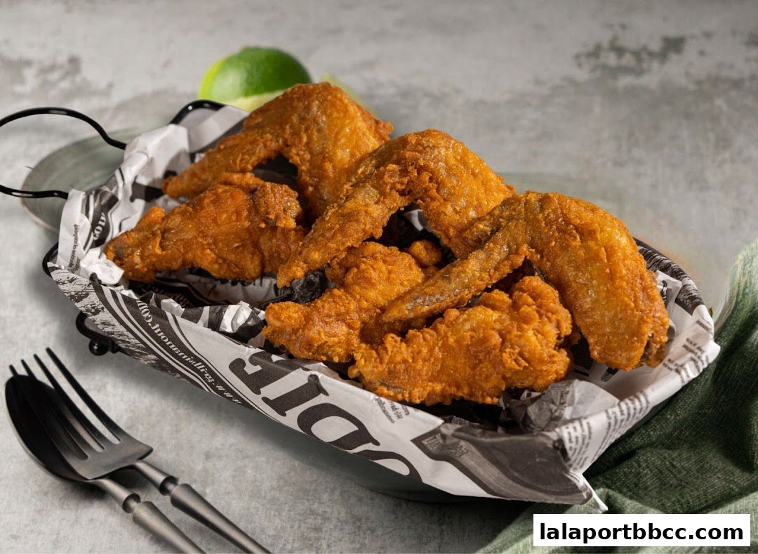 A basket of crispy, golden-brown fried chicken wings served with lime wedges.