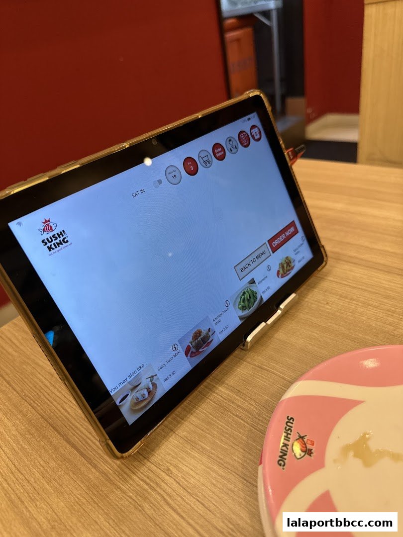 A tablet displaying the Sushi King menu and ordering interface on a wooden table.