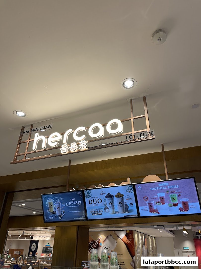 The Hercaa beverage shop's illuminated sign and digital menu boards displaying promotions.