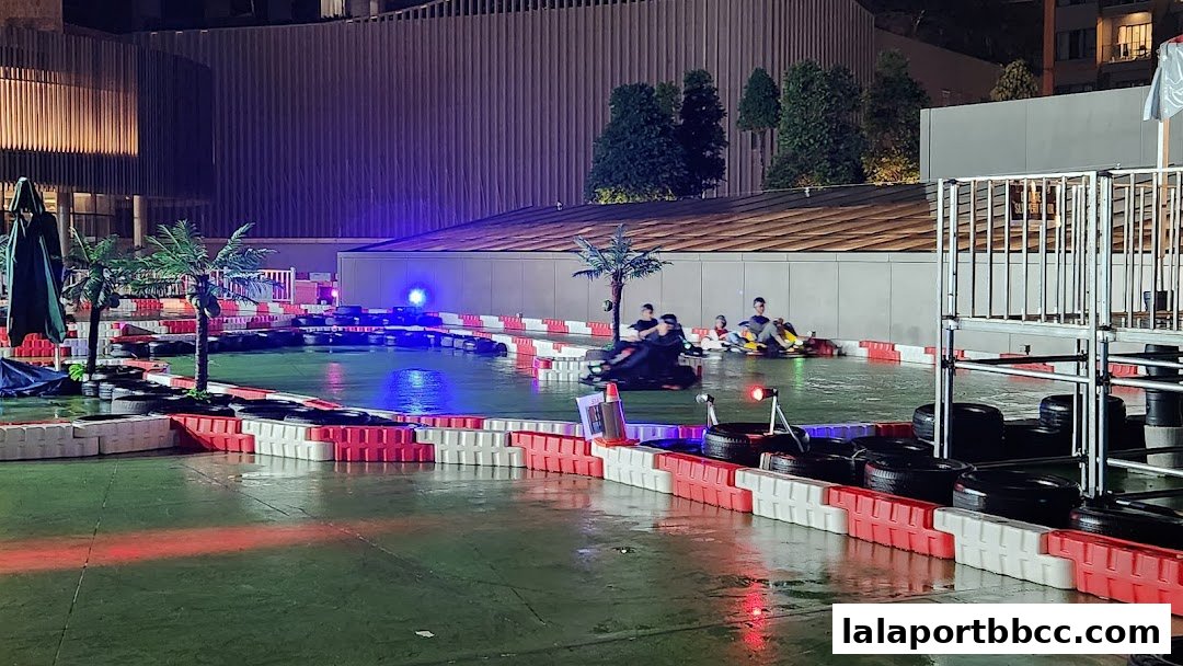 People racing go-karts on a wet track at night with colorful lighting.