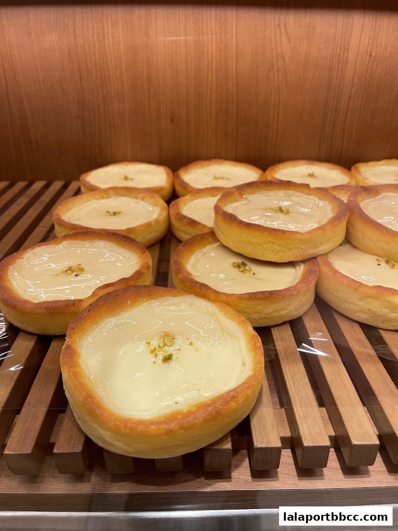 A close-up shot of several freshly baked tarts with creamy filling and chopped pistachios.