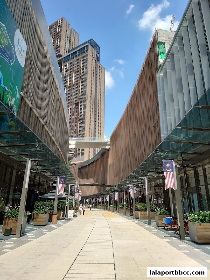 A wide pedestrian walkway lined with shops and modern architecture under a clear blue sky.