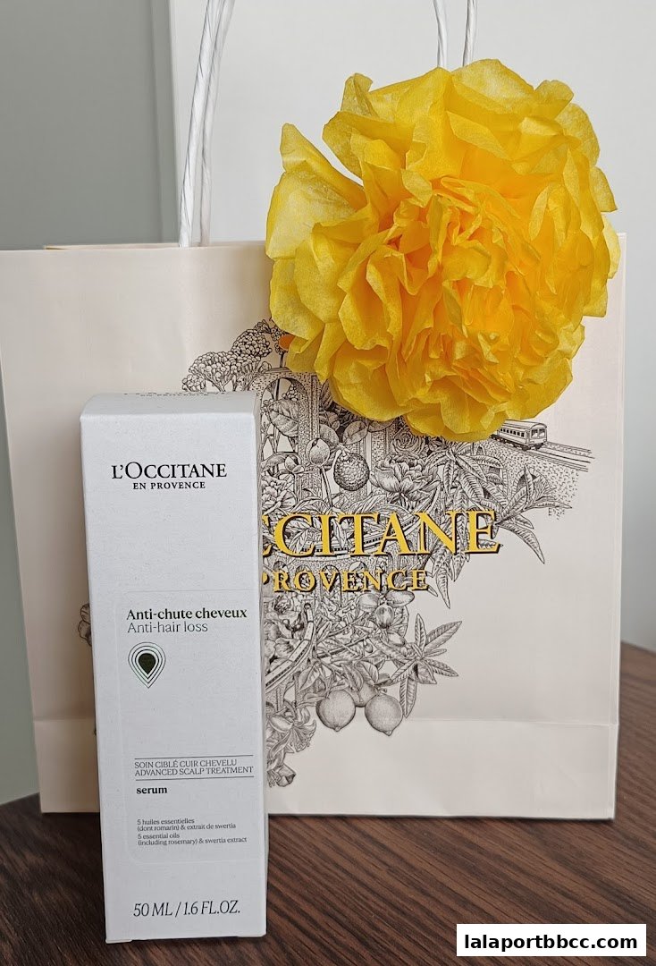 A L'Occitane anti-hair loss serum bottle and shopping bag with a yellow decoration.