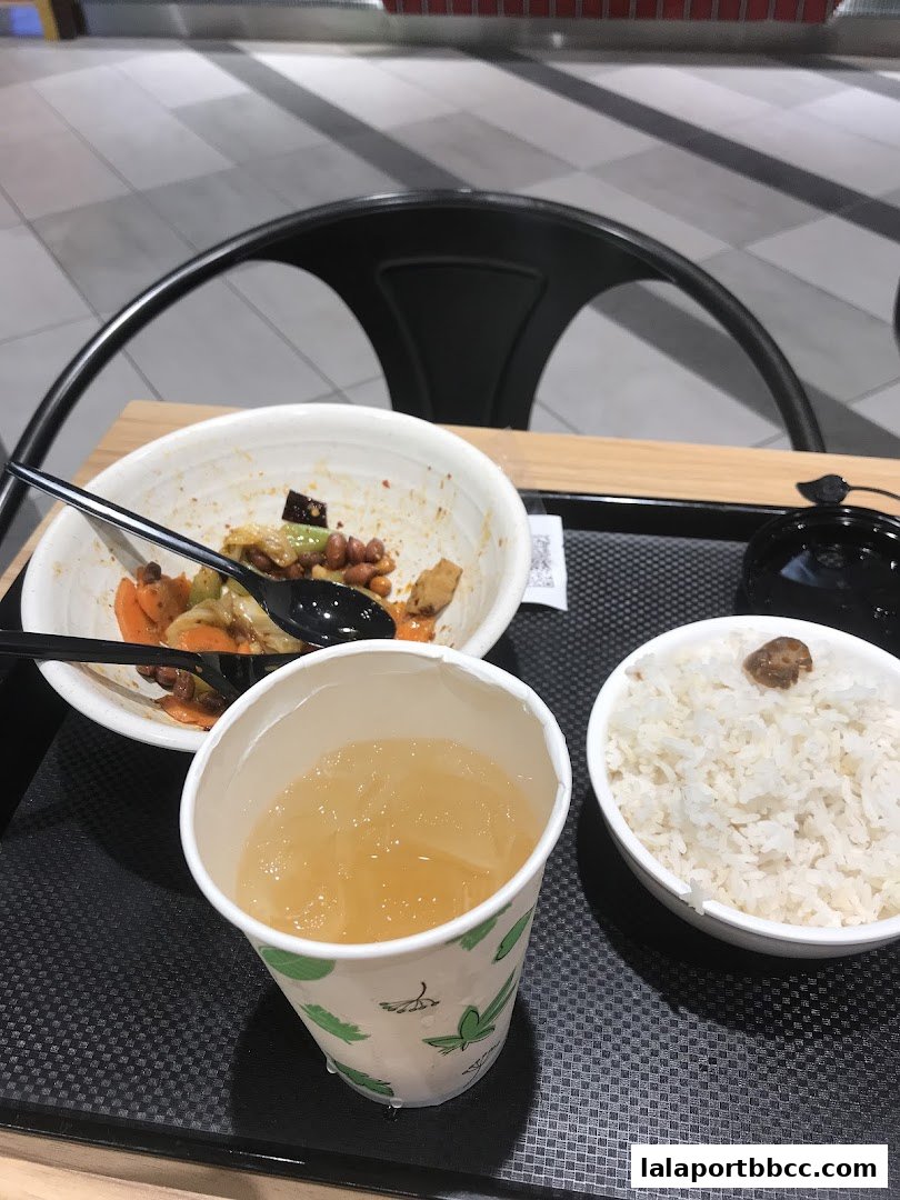 A tray with a bowl of fried rice, a cup of iced drink, and a bowl of rice.
