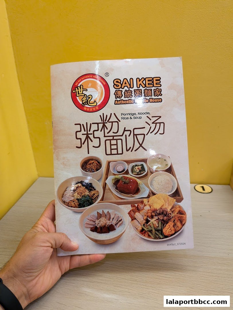 A hand holds a menu from Sai Kee Restaurant featuring various dishes like porridge, noodles, rice, and soup.