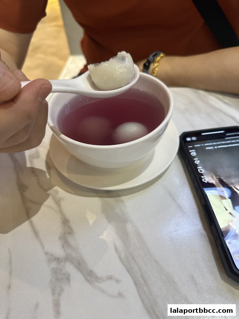 A person is eating a dessert with glutinous rice balls in a sweet soup.
