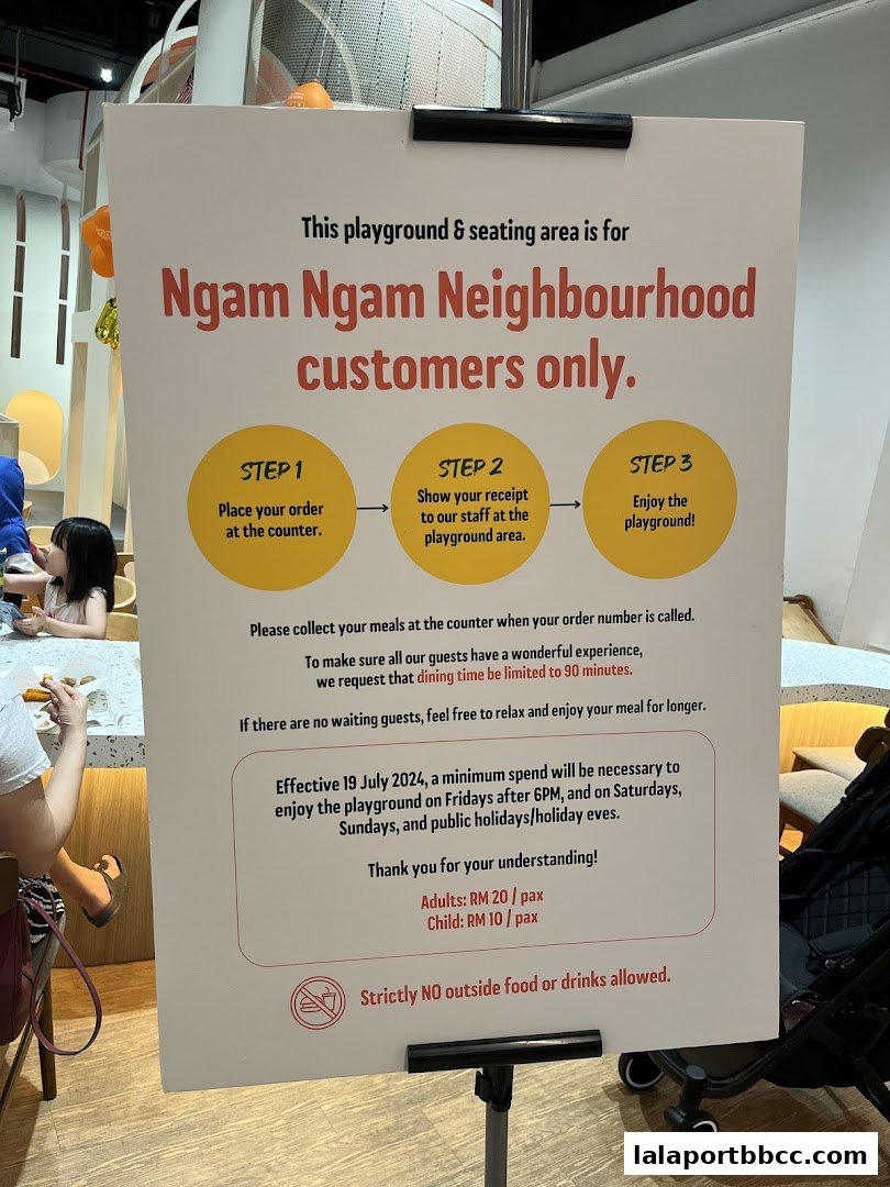 A sign detailing rules and pricing for a playground and seating area for Ngam Ngam Neighbourhood customers.