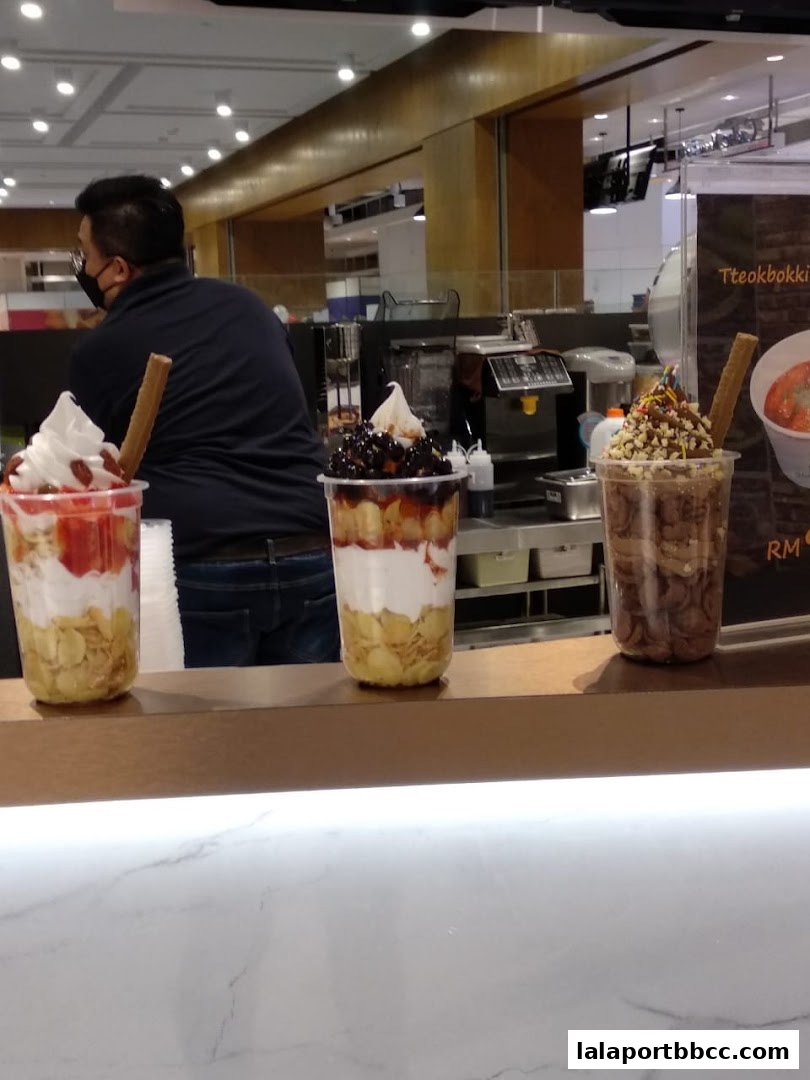 Three colorful ice cream desserts with toppings and a staff member behind the counter.