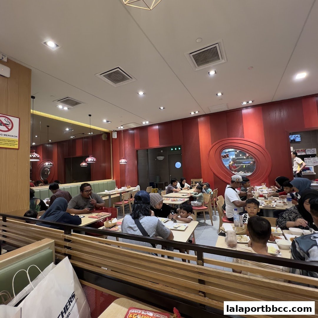 A busy restaurant interior with families dining at tables under red striped walls.