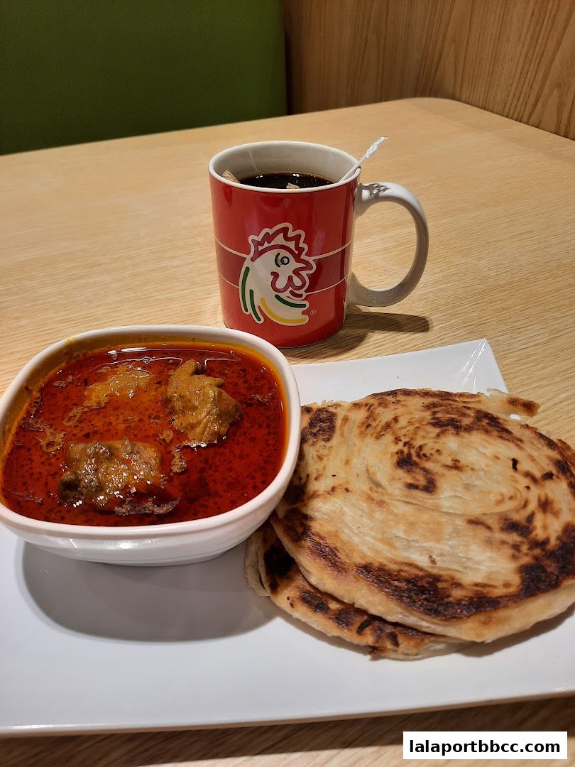 A bowl of curry with meat and roti, served with a mug of coffee.