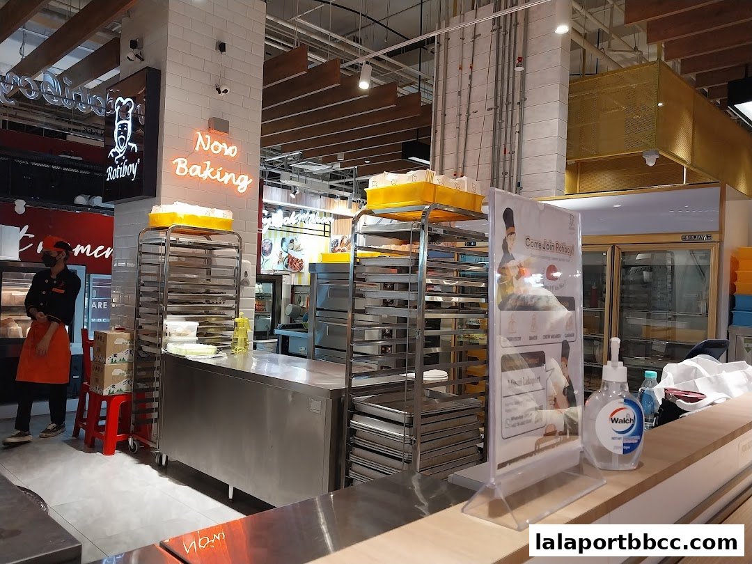 Interior view of a bakery with baking racks, a counter, and a staff member.