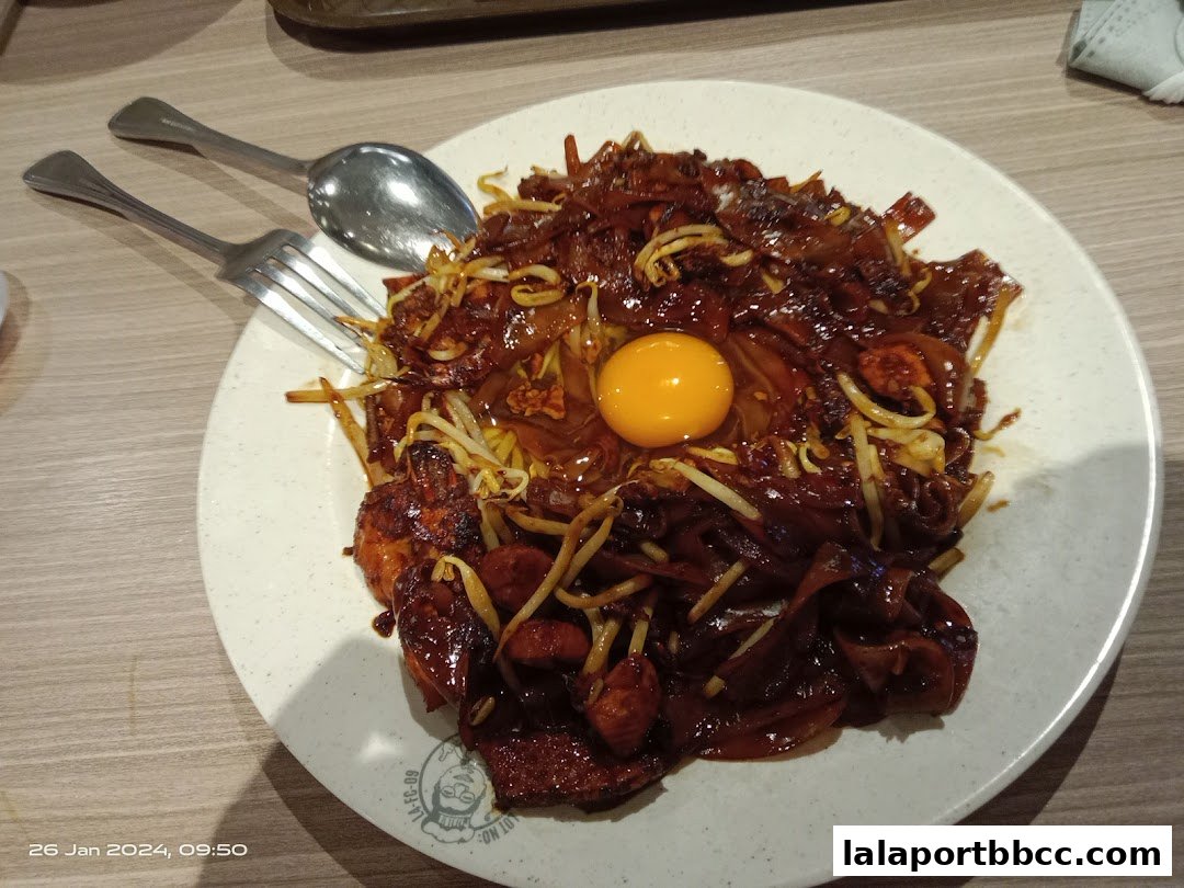 A plate of delicious Hokkien Mee with a raw egg yolk and fresh ingredients.