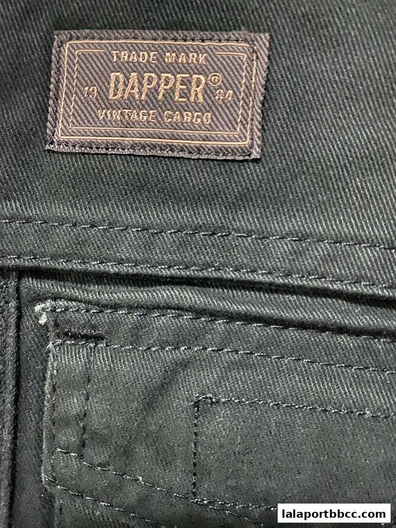 A close-up of a dark fabric with a stitched label reading 'Dapper Vintage Cargo'.