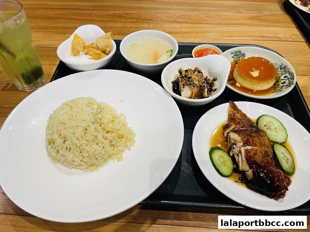 A tray of delicious chicken rice with sides, soup, and dessert.