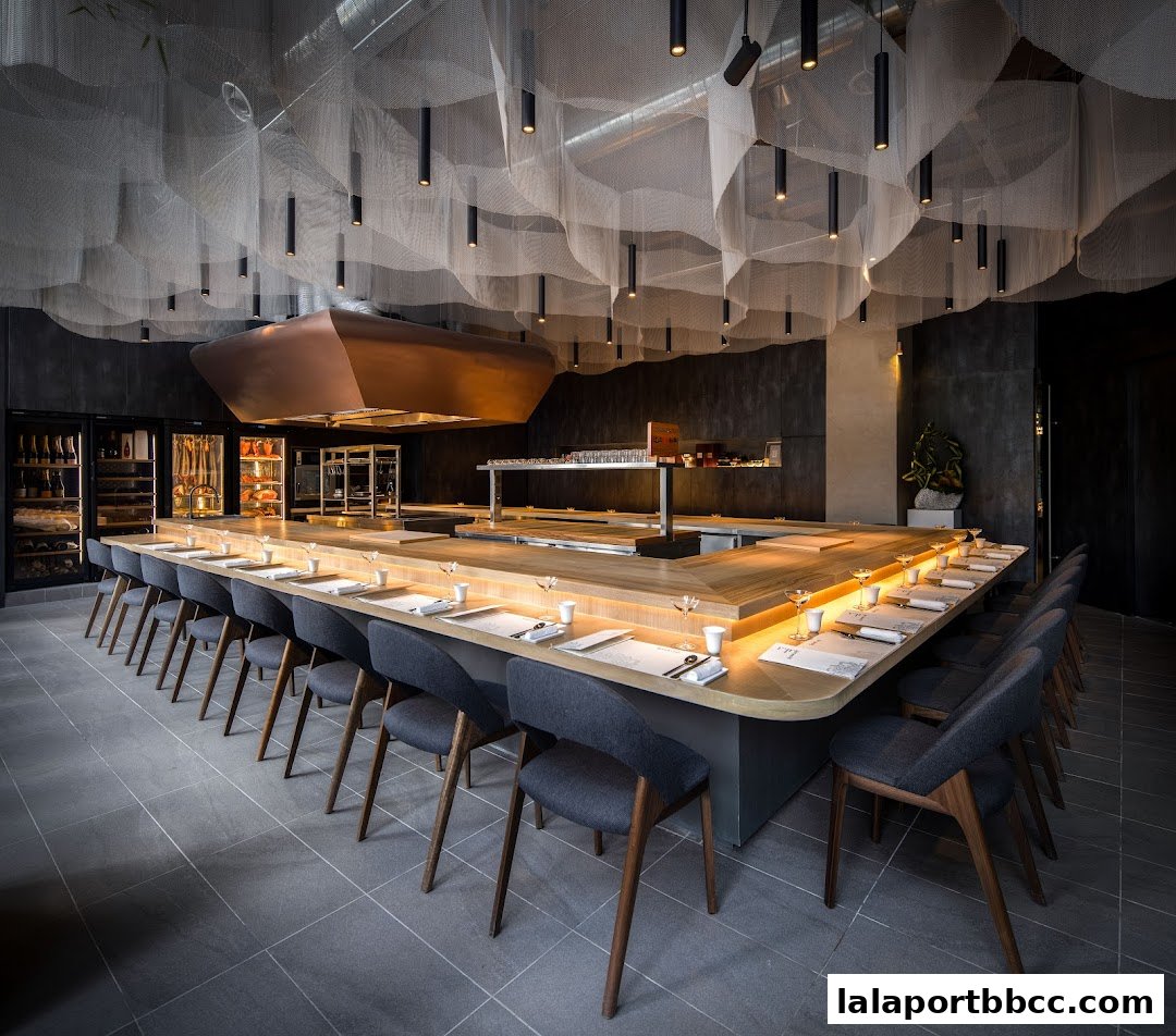 A modern restaurant interior with a long, illuminated sushi bar and seating.