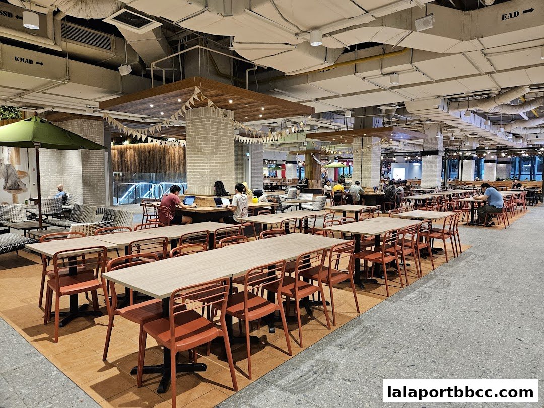 Spacious food court with many tables and chairs, some occupied by diners.