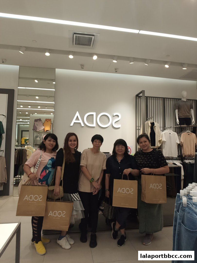 Five women pose for a photo inside a SODA store, holding shopping bags.