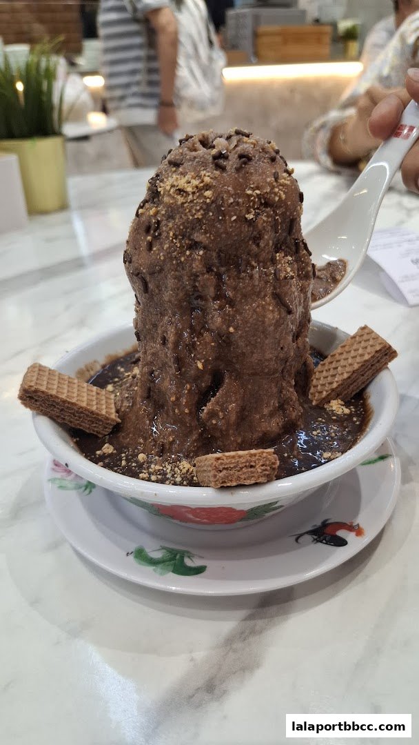 A tall serving of chocolate dessert with wafers and sprinkles, being scooped with a spoon.