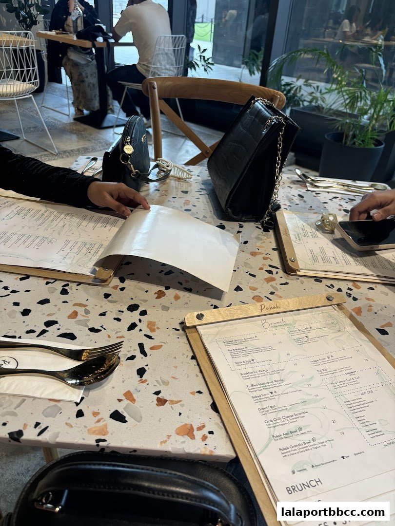 A table at POKOK LaLaport with menus and handbags, showing a brunch selection.