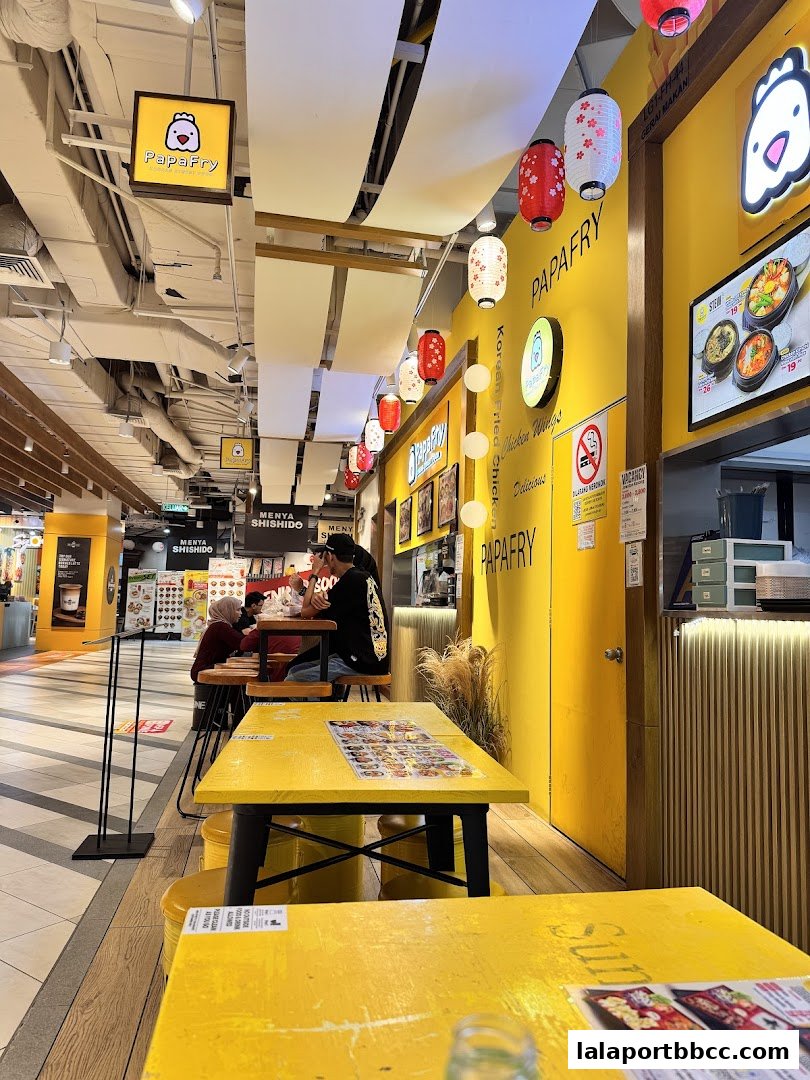 Interior view of PapaFry restaurant with yellow tables and Korean fried chicken decor.