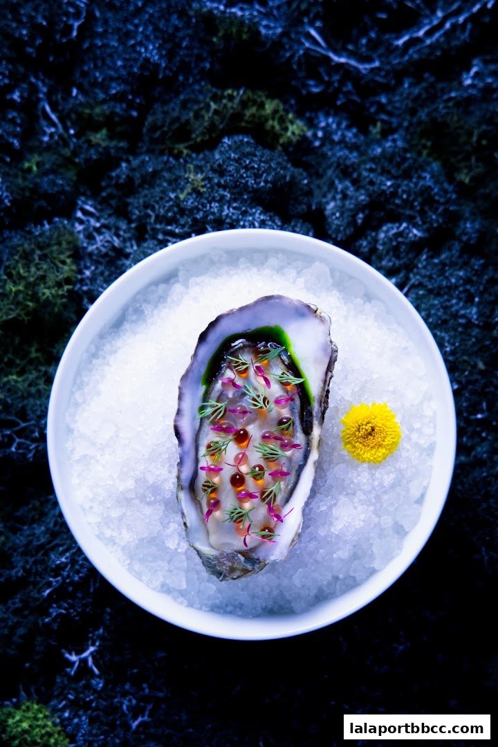 A beautifully presented oyster dish with delicate toppings and a small yellow flower on a bed of ice.