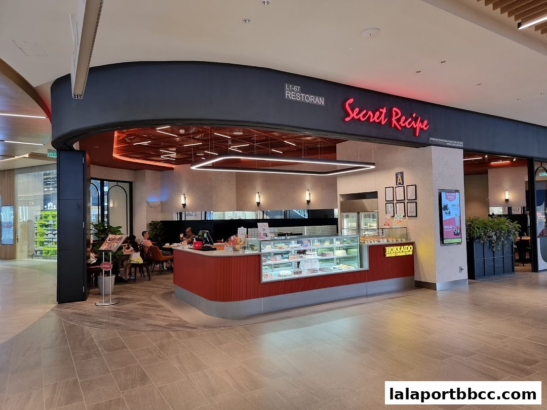 The exterior of a Secret Recipe cafe with a display of cakes and seating area.