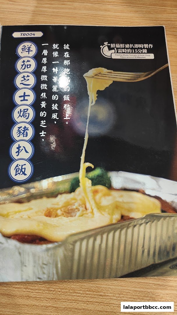 A close-up of a cheesy baked pork chop rice dish with Chinese text.