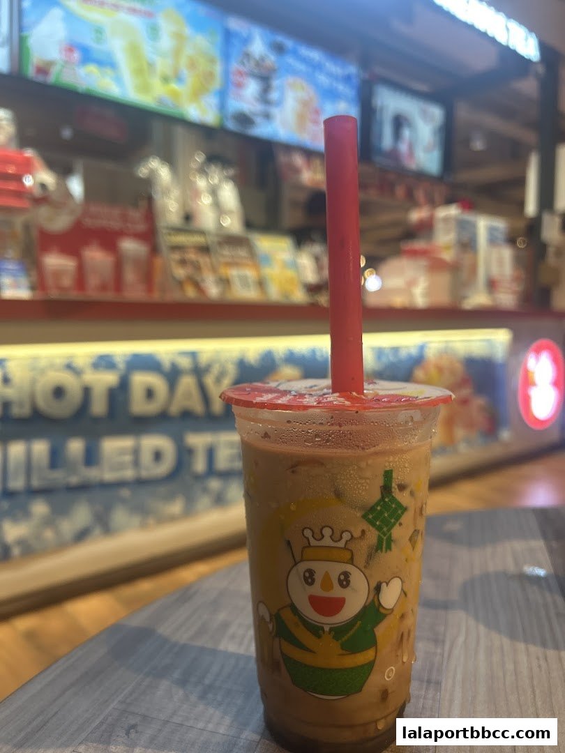 A close-up of a MIXUE drink with a red straw, featuring the brand's mascot.