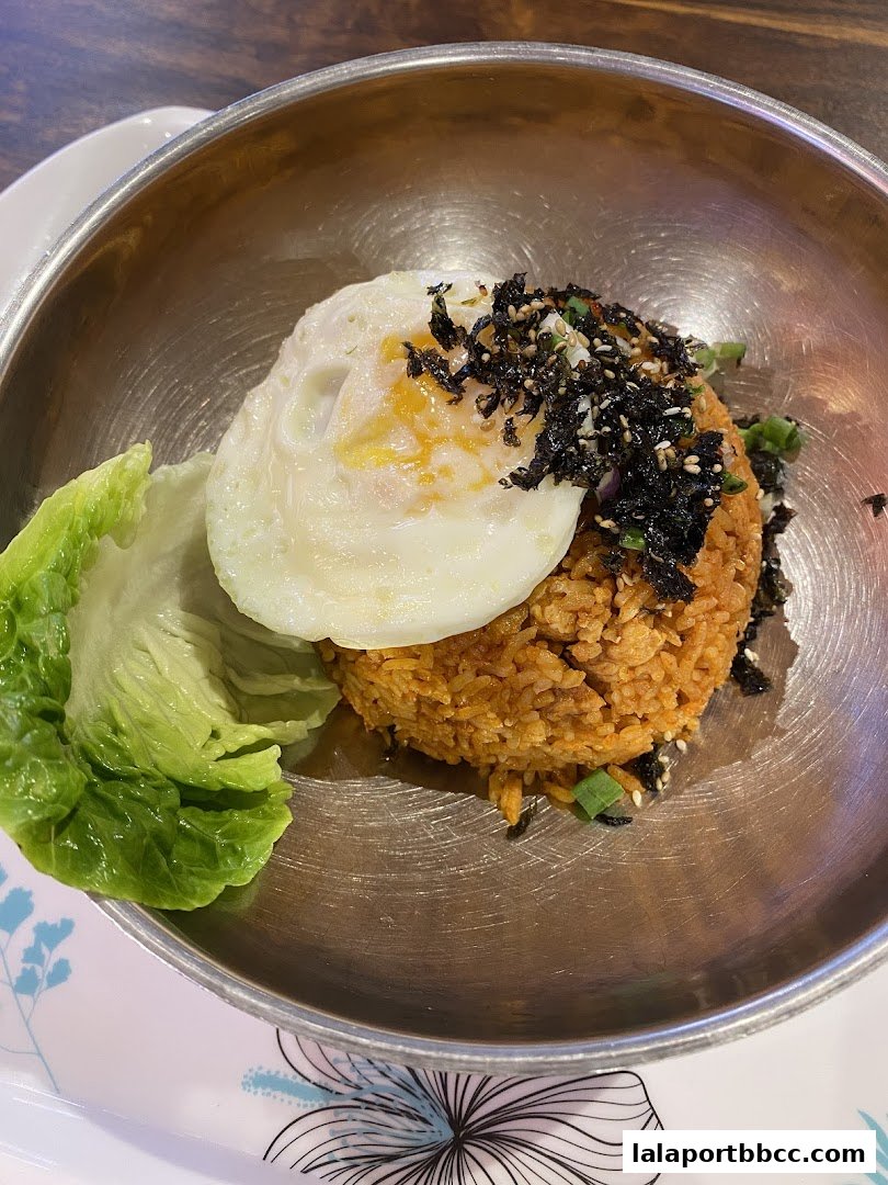 A close-up of a Korean fried rice dish topped with a fried egg and seaweed.