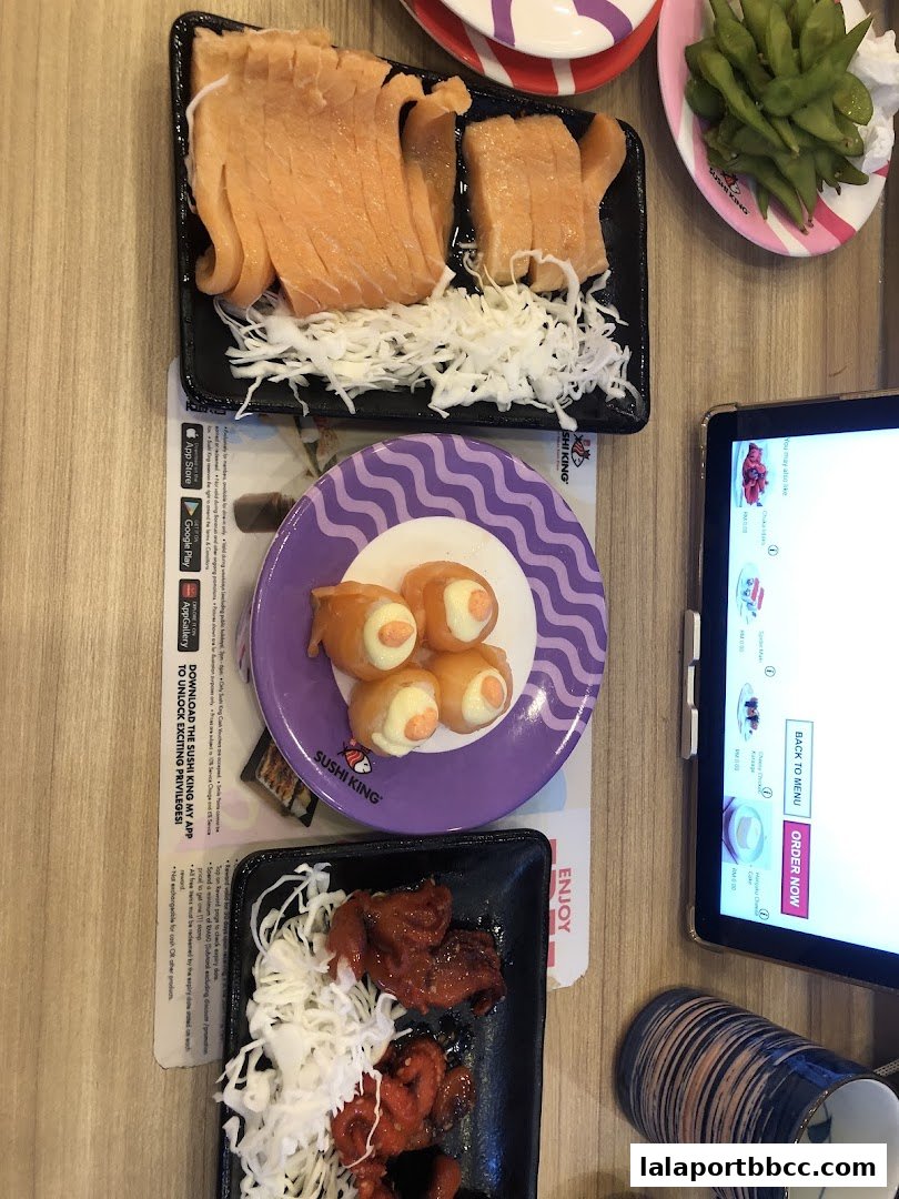 A table at Sushi King Lalaport BBCC with various sushi dishes and a tablet.
