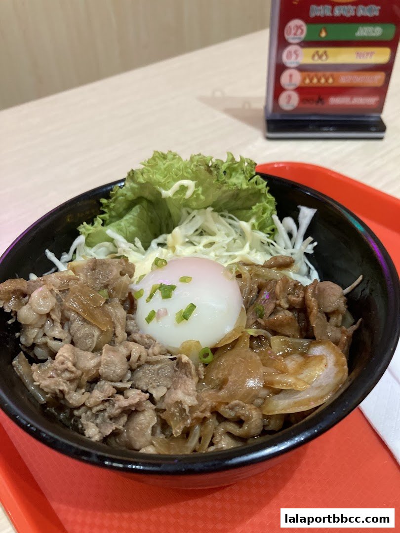 A close-up of a delicious beef curry rice bowl with a soft-boiled egg and fresh lettuce.