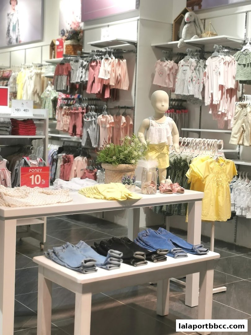 A brightly lit children's clothing store with racks of colorful apparel and a mannequin.