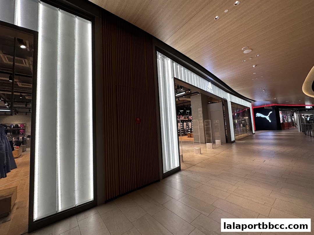 The modern storefront of an Adidas Originals shop with illuminated panels and wooden accents.