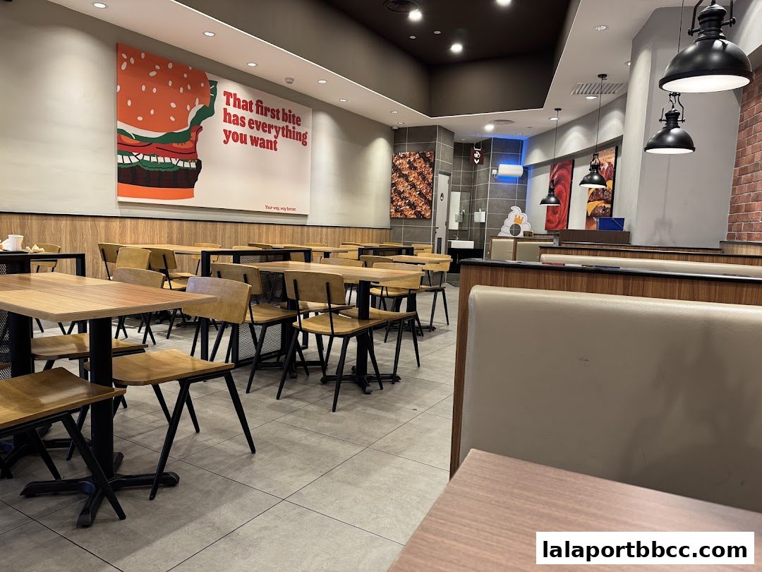 Interior of a Burger King restaurant with tables, chairs, and large promotional posters.