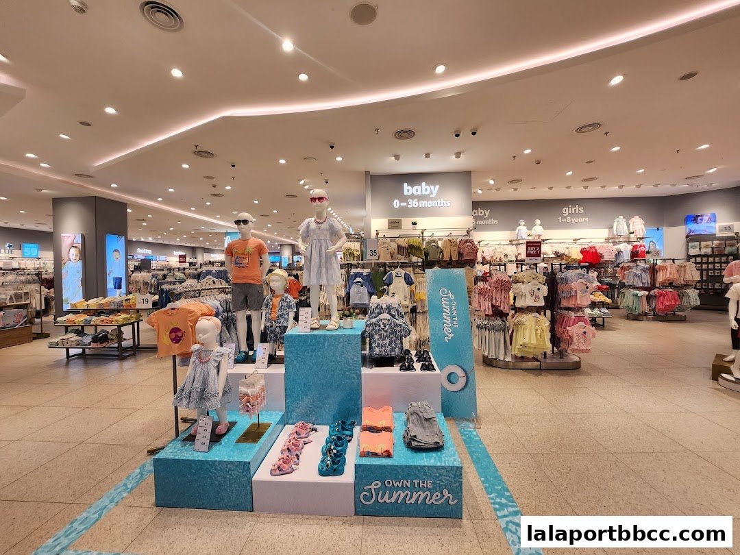 Interior view of a brightly lit children's clothing store with mannequins and racks of clothes.