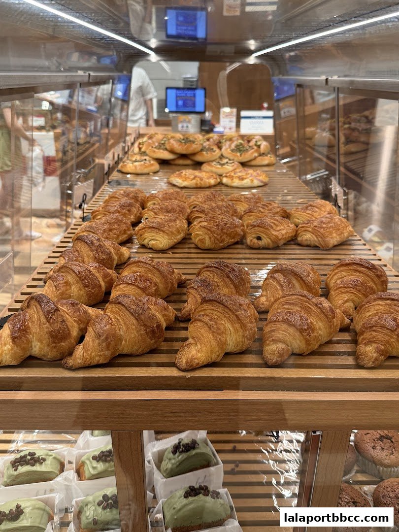 A display case filled with freshly baked croissants and pastries, including green tea cakes.