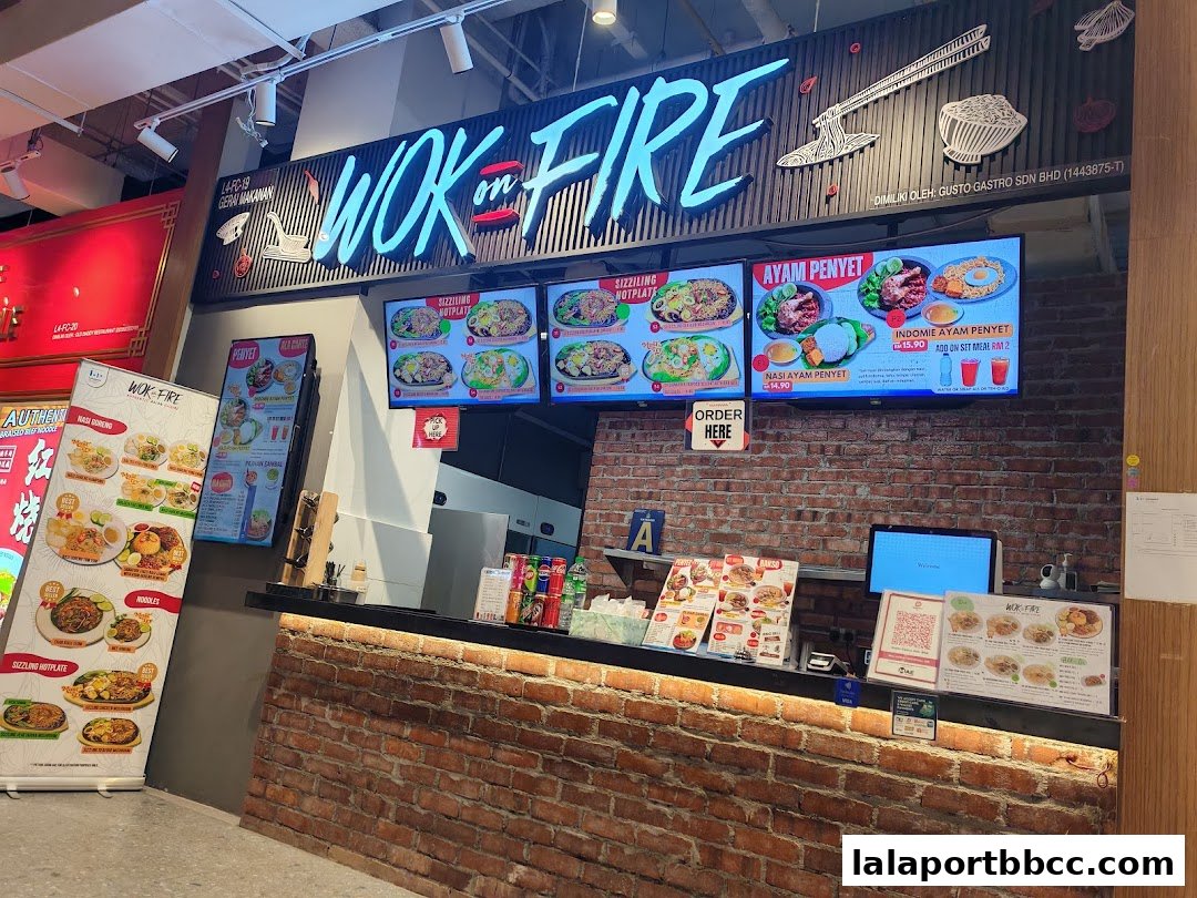 A food court stall with a prominent 'WOK in FIRE' sign and digital menu displays.