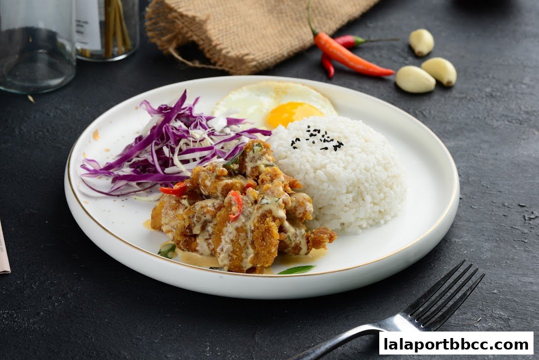 A plate of crispy chicken with rice, fried egg, and shredded red cabbage.