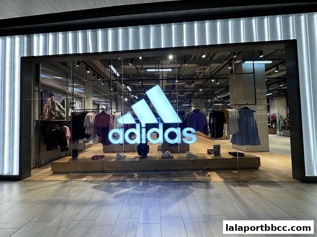 The exterior of an Adidas Originals store with its iconic logo and displayed apparel.