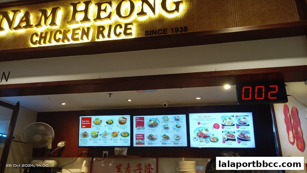 Digital menu boards displaying various chicken rice dishes and set meals at Nam Heong Chicken Rice.
