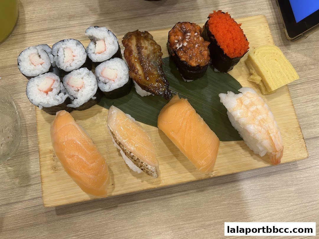 A wooden platter filled with various types of sushi, including salmon, shrimp, and maki rolls.