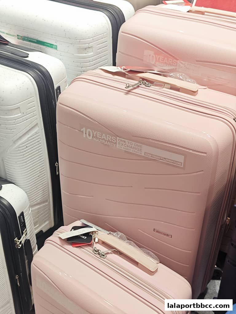 A close-up view of several pink and white suitcases, some with '10 Years Warranty' labels.