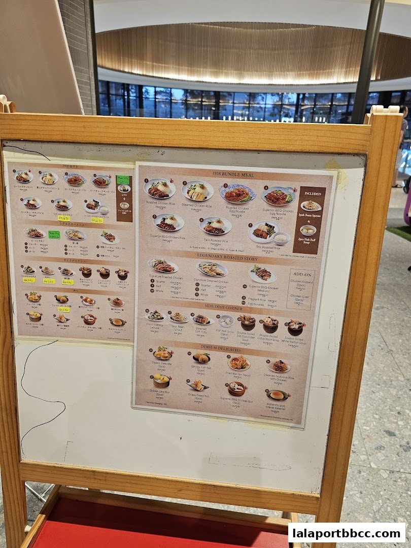 A wooden easel displays a menu for Nam Heong Chicken Rice with various dishes and prices.