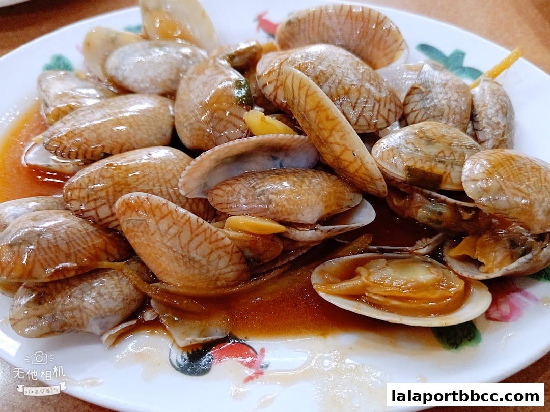 A close-up shot of a plate of delicious stir-fried clams in a savory sauce.