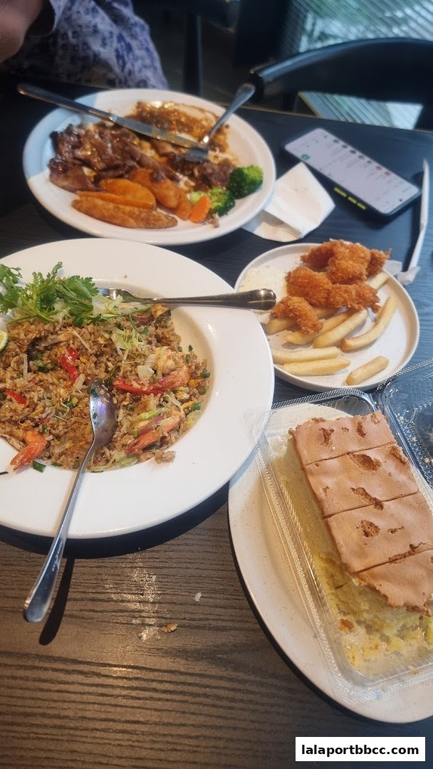 A table laden with various dishes including fried rice, steak, fries, and dessert.
