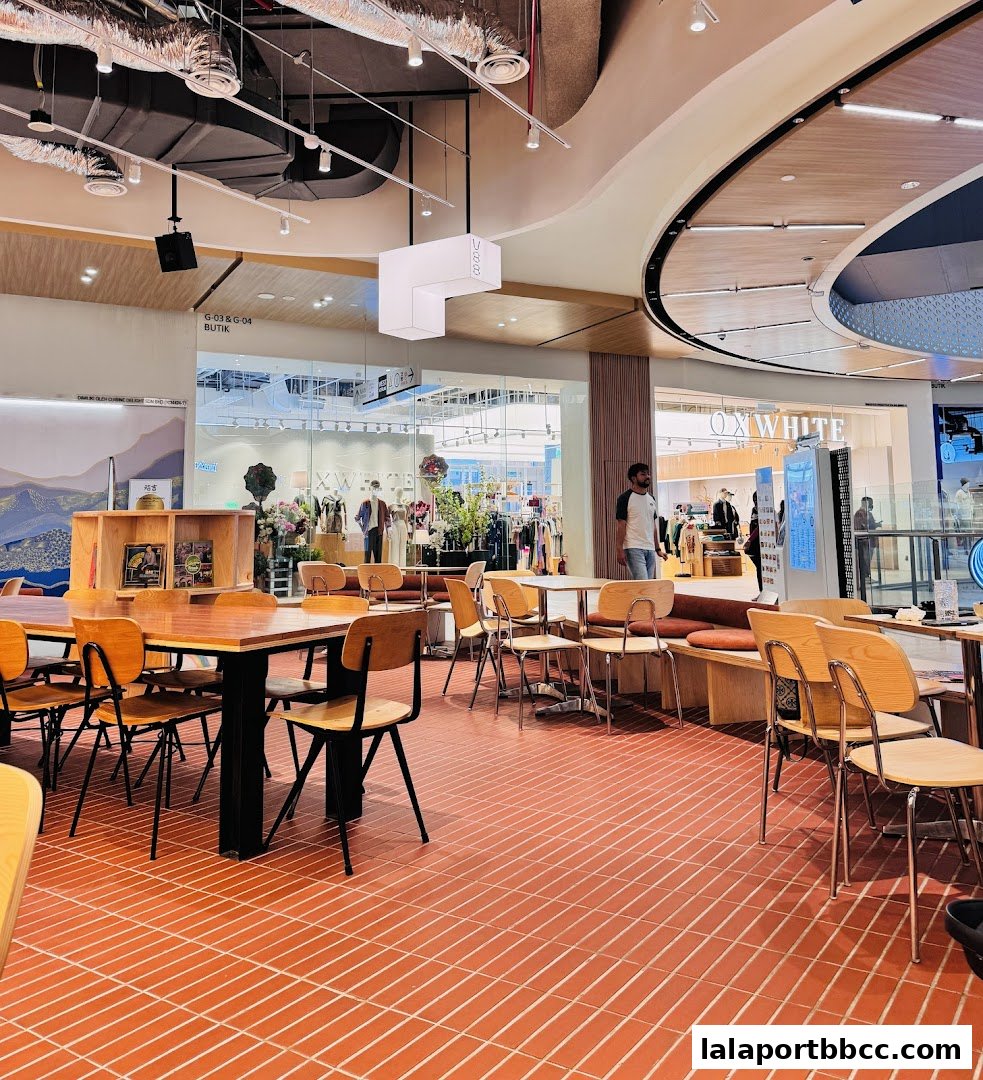 Interior of a cafe and bar with wooden tables, chairs, and a view of shops.