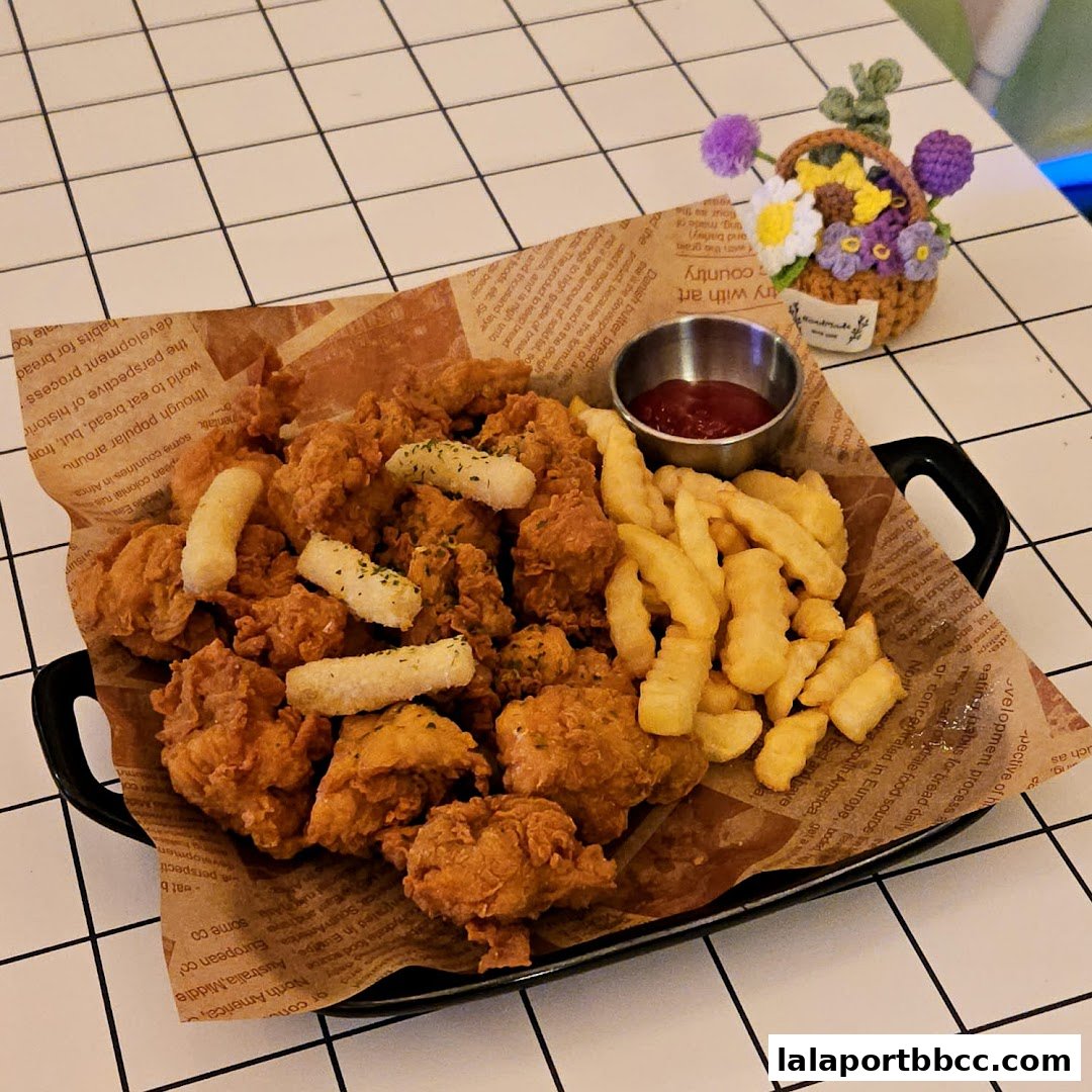 A plate of crispy fried chicken and french fries with a small cup of ketchup.