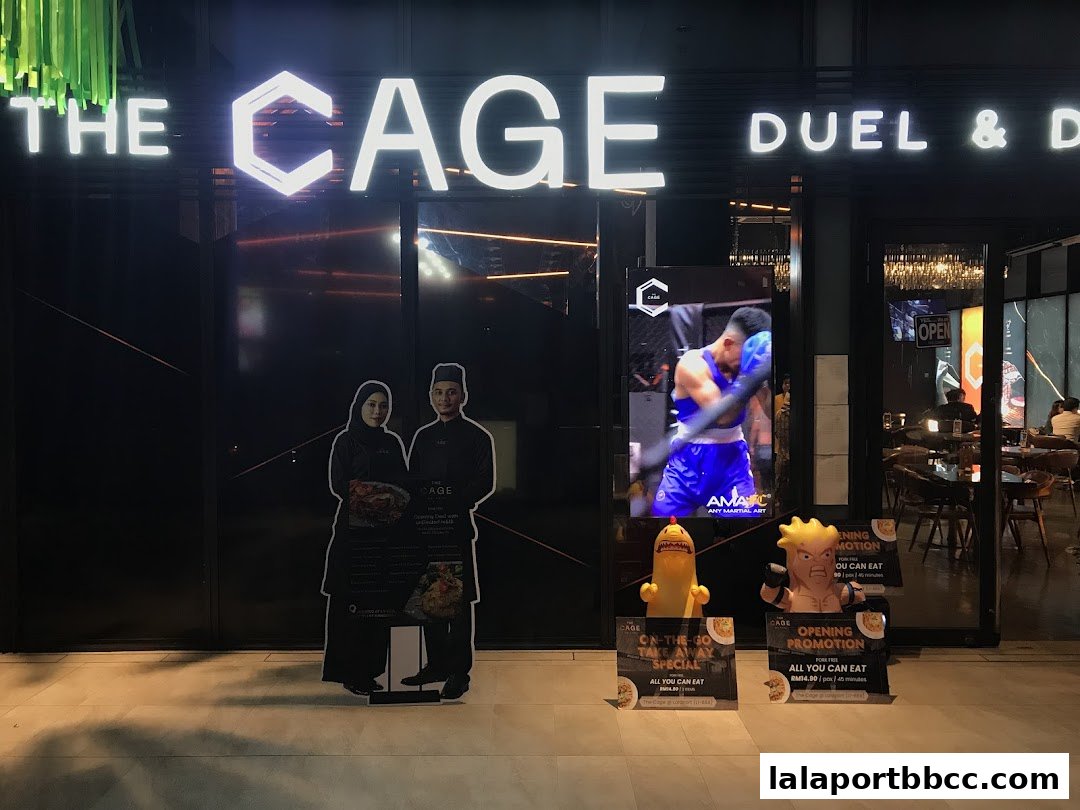 The exterior of 'The CAGE - Duel & Dine' restaurant with neon signage and promotional displays.